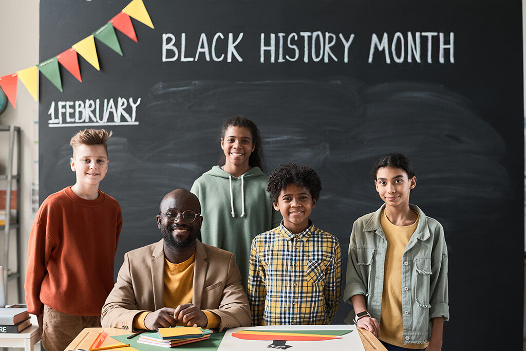 Group of diverse students with "black history month" written on a whiteboard behind them